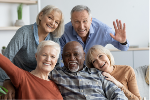 xfive seniors sitting on a couch embracing each other and smiling in a Pembroke Pines assisted living facility