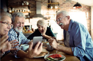 A group of seniors around a table in their senior living community smiling and laughing